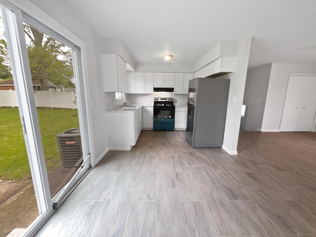 kitchen with freestanding refrigerator, electric range oven, a sink, under cabinet range hood, and light countertops