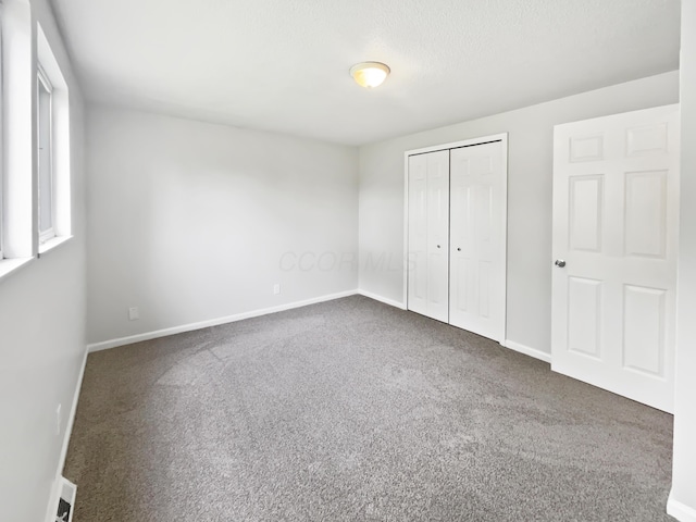 unfurnished bedroom featuring carpet flooring, baseboards, and a closet