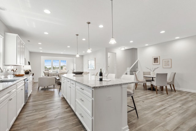 6039 Peck Ln, New Albany, OH 43054 - kitchen featuring a breakfast bar, open floor plan, light wood-style flooring, recessed lighting, and white cabinets