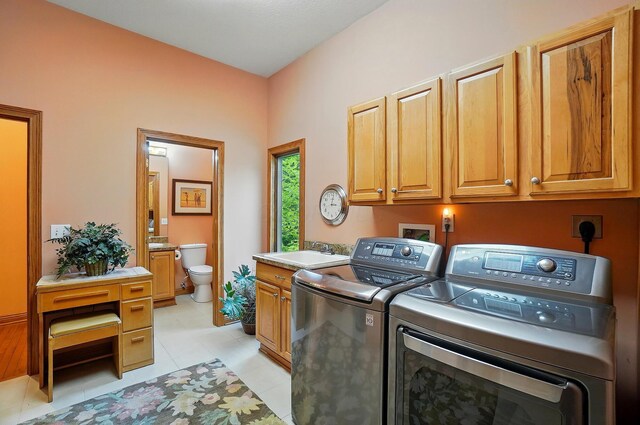 1092 George Allen Dr, South Vienna, OH 45369 - clothes washing area featuring washing machine and dryer, cabinet space, and light tile patterned floors