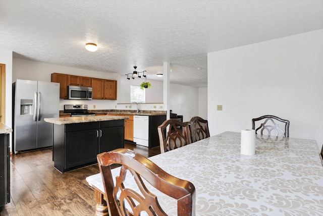 5504 Rothermund Dr, Canal Winchester, OH 43110 - kitchen featuring appliances with stainless steel finishes, dark wood-type flooring, a kitchen island, a textured ceiling, and a sink