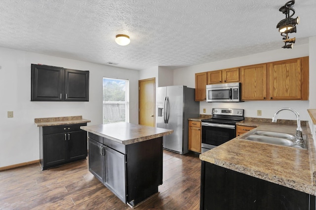 5504 Rothermund Dr, Canal Winchester, OH 43110 - kitchen featuring appliances with stainless steel finishes, a sink, a textured ceiling, a kitchen island, and dark wood-style flooring