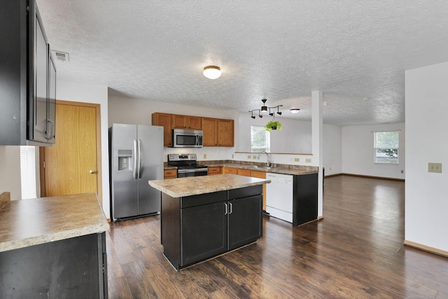 5504 Rothermund Dr, Canal Winchester, OH 43110 - kitchen with appliances with stainless steel finishes, a kitchen island, a sink, dark wood-style floors, and light countertops