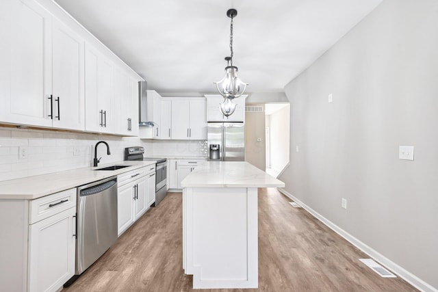 434 S Champion Ave, Columbus, OH 43205 - kitchen featuring appliances with stainless steel finishes, tasteful backsplash, light wood-style floors, wall chimney exhaust hood, and a center island