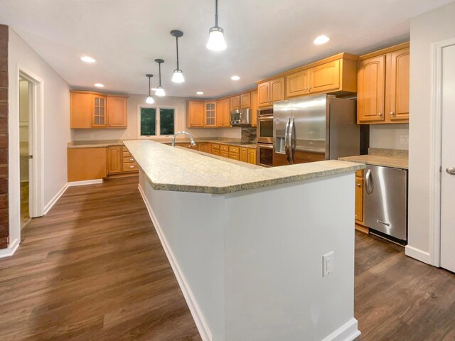642 Ridenour Rd, Columbus, OH 43230 - kitchen featuring appliances with stainless steel finishes, dark wood-style flooring, baseboards, an island with sink, and recessed lighting