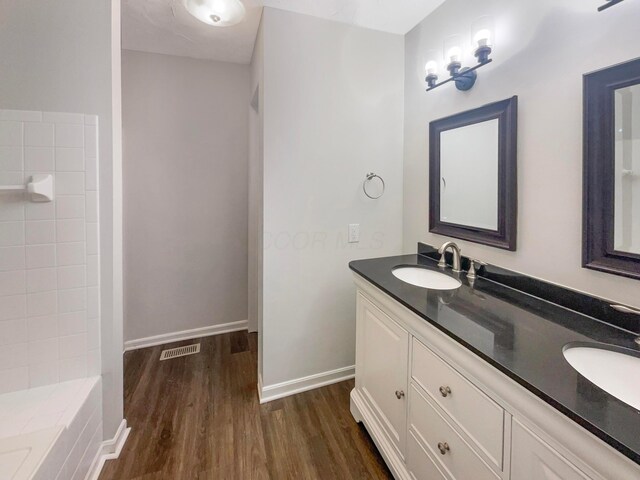 642 Ridenour Rd, Columbus, OH 43230 - bathroom featuring wood finished floors, double vanity, baseboards, and a bath