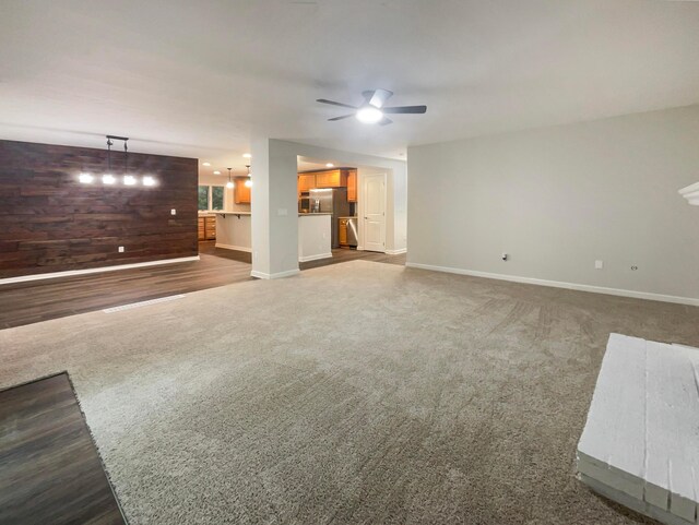 642 Ridenour Rd, Columbus, OH 43230 - unfurnished living room featuring baseboards, ceiling fan, dark carpet, and wooden walls