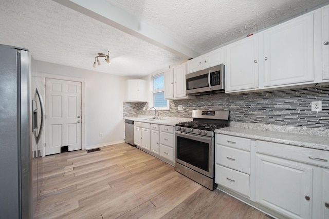 799 E Deshler Ave, Columbus, OH 43206 - kitchen featuring appliances with stainless steel finishes, a sink, white cabinets, light wood-type flooring, and a textured ceiling