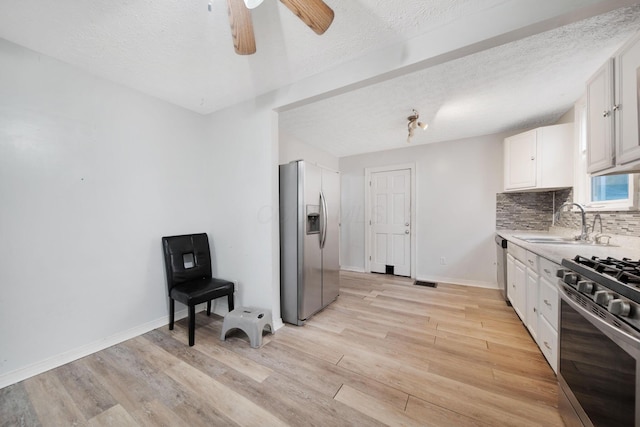 799 E Deshler Ave, Columbus, OH 43206 - kitchen with appliances with stainless steel finishes, a sink, light wood finished floors, backsplash, and ceiling fan
