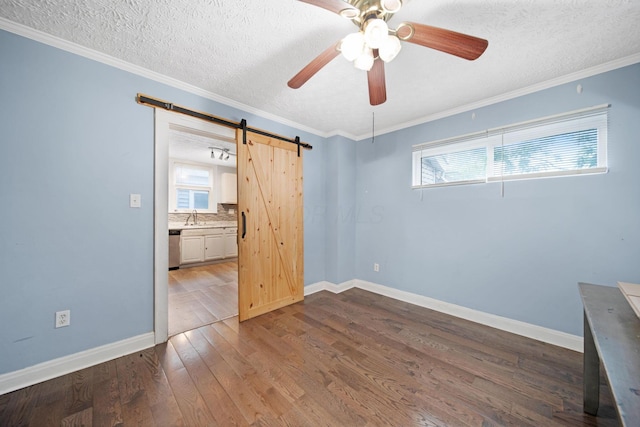 799 E Deshler Ave, Columbus, OH 43206 - unfurnished bedroom with a barn door, a sink, multiple windows, dark wood finished floors, and a textured ceiling