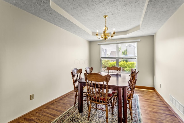 917 Linkfield Dr, Columbus, OH 43085 - dining space featuring a textured ceiling, a tray ceiling, a chandelier, wood finished floors, and baseboards