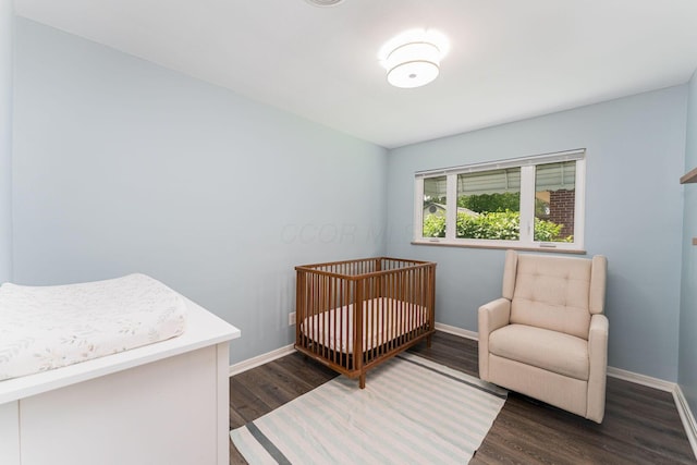 205 Meadowlark Ln, Columbus, OH 43214 - bedroom featuring dark wood-style floors, baseboards, and a crib