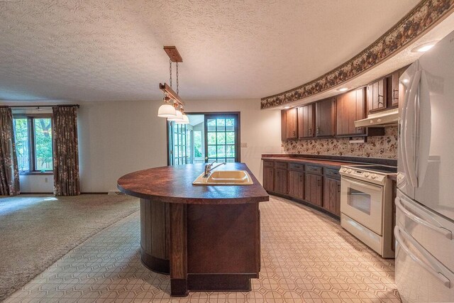 735 Cherrington Rd, Westerville, OH 43081 - kitchen with white appliances, a sink, dark countertops, under cabinet range hood, and an island with sink