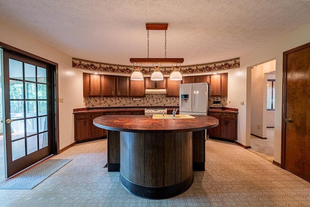735 Cherrington Rd, Westerville, OH 43081 - kitchen featuring white refrigerator with ice dispenser, dark countertops, under cabinet range hood, a sink, and decorative backsplash