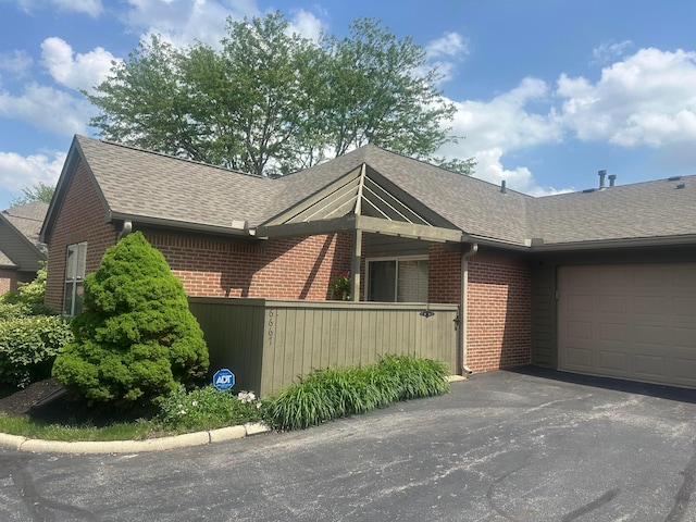 6667 Heatherstone Loop, Dublin, OH 43017 - view of property exterior with brick siding, a garage, driveway, roof with shingles, and fence