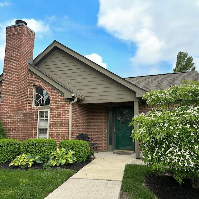 6667 Heatherstone Loop, Dublin, OH 43017 - view of exterior entry featuring brick siding, a chimney, and a shingled roof