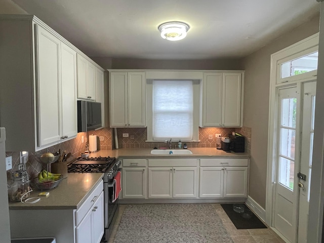 91 Oakland Park Ave, Columbus, OH 43214 - kitchen with stainless steel range with gas cooktop, a sink, white cabinetry, decorative backsplash, and light countertops