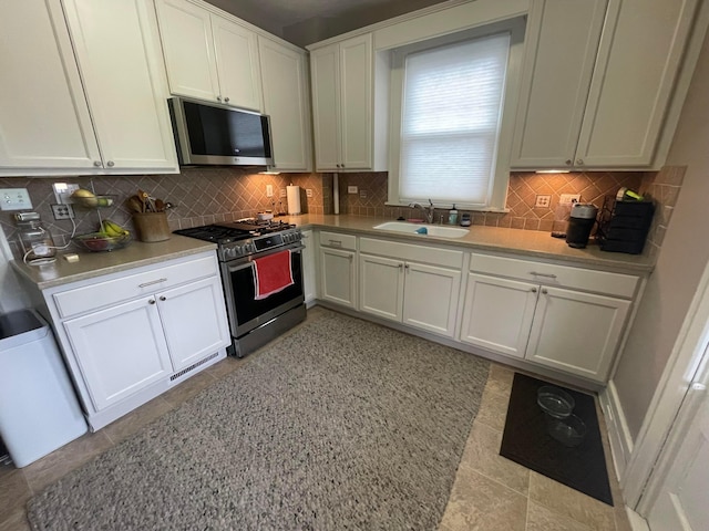 91 Oakland Park Ave, Columbus, OH 43214 - kitchen featuring appliances with stainless steel finishes, a sink, decorative backsplash, and white cabinetry