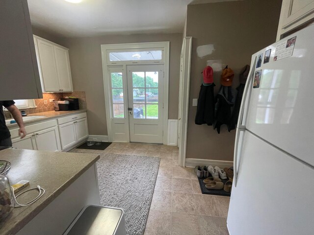 91 Oakland Park Ave, Columbus, OH 43214 - kitchen with freestanding refrigerator, decorative backsplash, baseboards, and white cabinets
