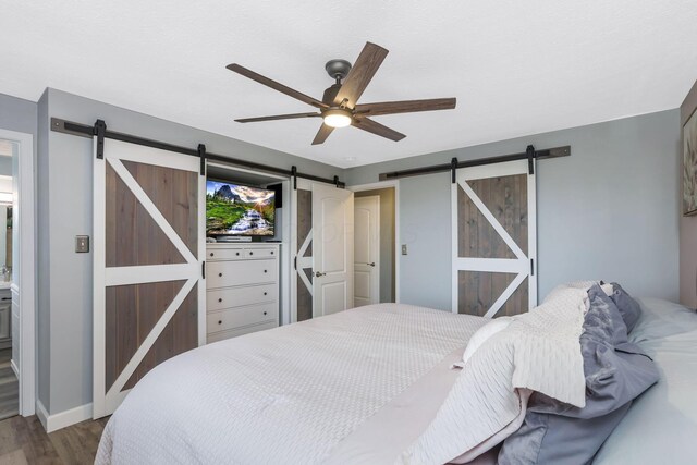 8485 Benson Rd NW, Carroll, OH 43112 - bedroom featuring a barn door, wood finished floors, a ceiling fan, and baseboards
