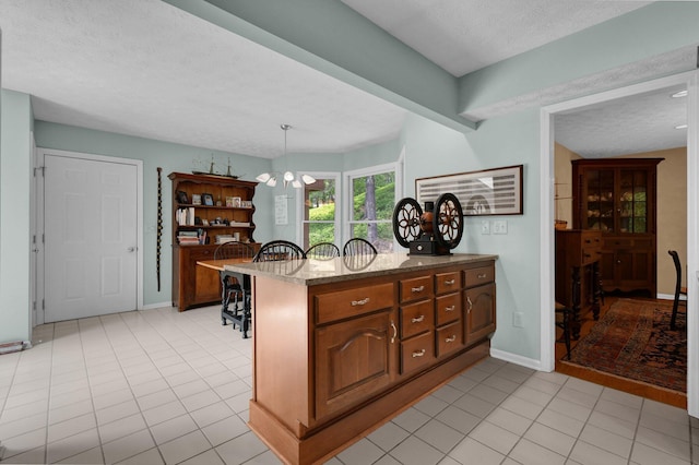 71 Donald Ross Dr, Granville, OH 43023 - kitchen with a textured ceiling, light tile patterned floors, light stone counters, a peninsula, and brown cabinetry