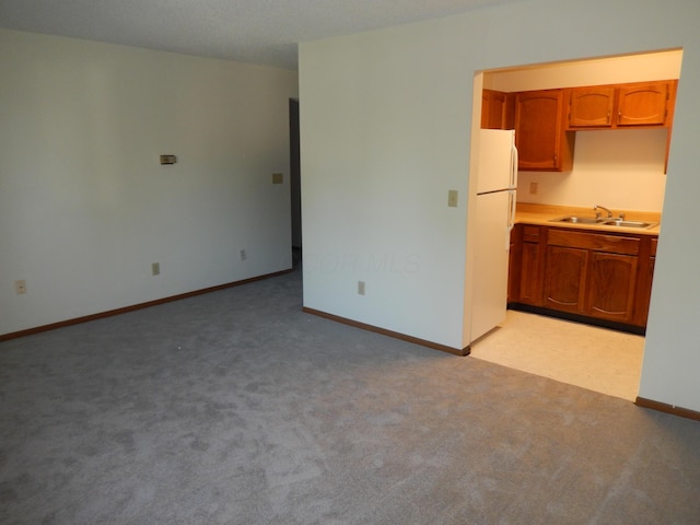 4143 Karl Rd Unit 214, Columbus, OH 43224 - kitchen featuring a sink, freestanding refrigerator, brown cabinets, and baseboards