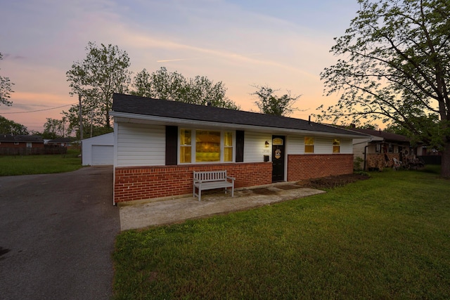 view of front of home with brick siding, a front lawn, a garage, covered porch, and asphalt driveway