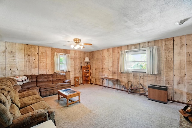 carpeted living room with plenty of natural light, wood walls, and ceiling fan