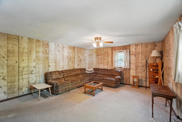 living room featuring a ceiling fan, wooden walls, and carpet floors