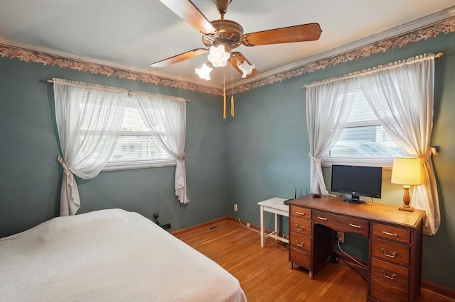 bedroom with light wood-style floors, an office area, ceiling fan, and baseboards
