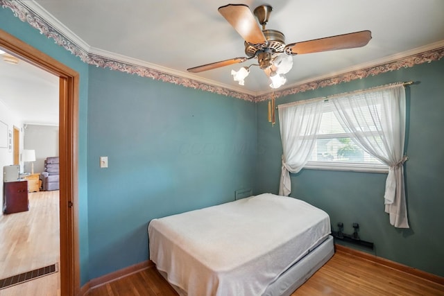 bedroom featuring wood finished floors, a ceiling fan, crown molding, and baseboards