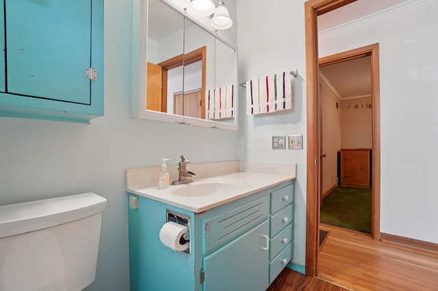 half bathroom featuring wood finished floors, toilet, vanity, and baseboards
