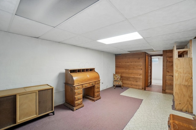 unfurnished office featuring a paneled ceiling and wood walls
