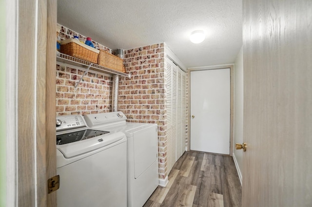 2675 Pine Marsh Dr, Grove City, OH 43123 - laundry room with washing machine and dryer, wood finished floors, brick wall, a textured ceiling, and baseboards