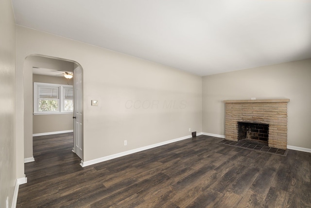 624 Bendle Ave, Shelby, OH 44875 - unfurnished living room with dark wood-style flooring, arched walkways, baseboards, a fireplace, and ceiling fan