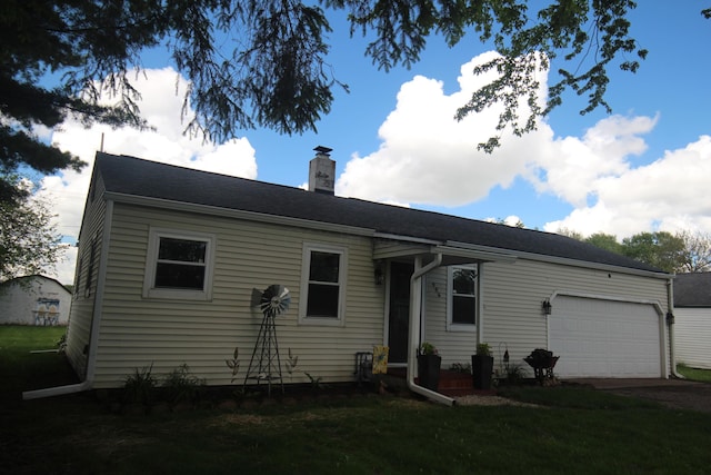 view of front of home featuring an attached garage, a chimney, and a front yard