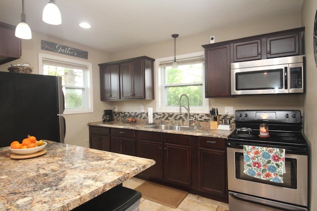 kitchen featuring appliances with stainless steel finishes, a sink, dark brown cabinets, decorative light fixtures, and recessed lighting