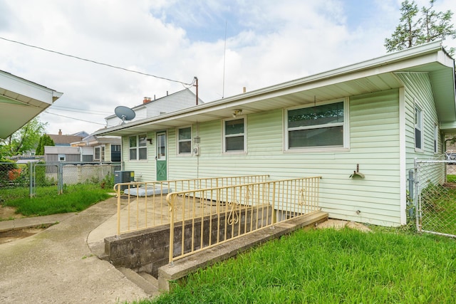 rear view of property featuring fence and central AC unit