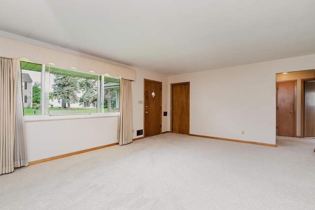 unfurnished room featuring light carpet and baseboards