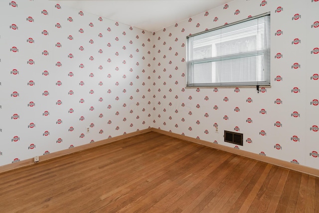 spare room featuring wallpapered walls, light wood finished floors, and baseboards