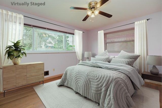 bedroom with light wood finished floors, baseboards, and ceiling fan