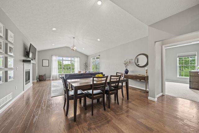 1070 Little Bear Pl, Lewis Center, OH 43035 - dining area featuring vaulted ceiling, dark wood finished floors, a glass covered fireplace, plenty of natural light, and a chandelier