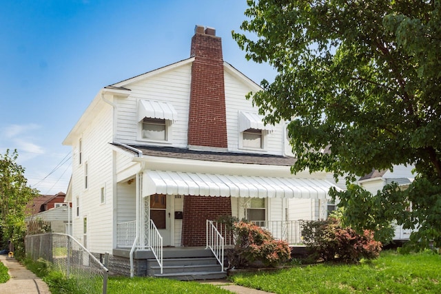 view of front of home featuring a chimney, roof with shingles, and covered porch
