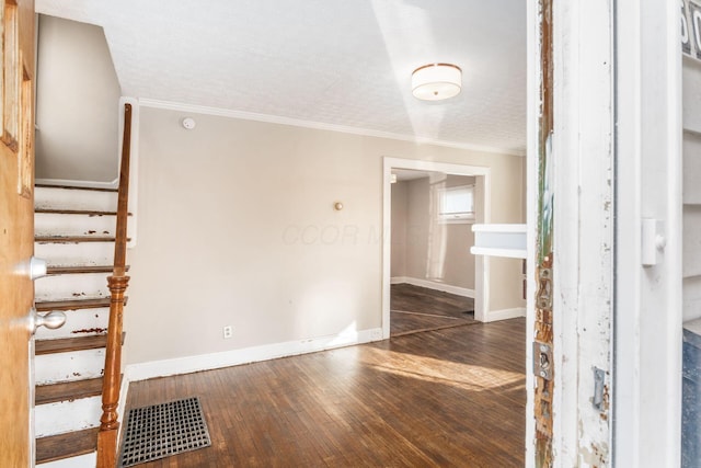 spare room with hardwood / wood-style flooring, crown molding, baseboards, and stairway
