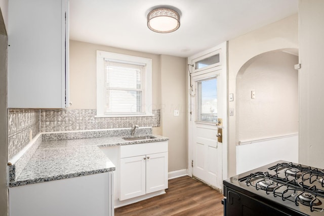 kitchen with a sink, white cabinets, decorative backsplash, dark wood-style floors, and plenty of natural light