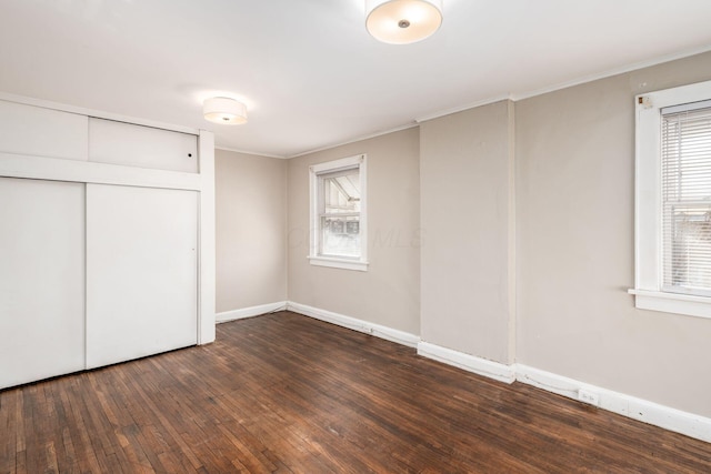 unfurnished bedroom with hardwood / wood-style floors, multiple windows, ornamental molding, and baseboards