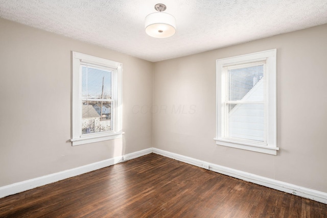 spare room featuring baseboards, dark wood-style flooring, and a textured ceiling