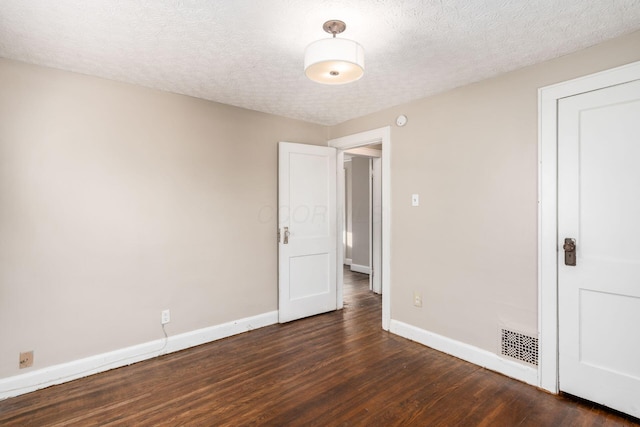 unfurnished room featuring dark wood-type flooring, baseboards, and a textured ceiling