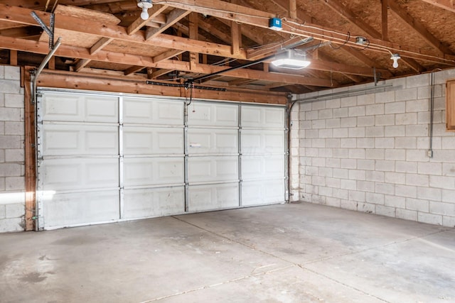 garage with a garage door opener and concrete block wall