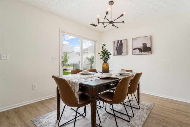 1993 Cumberland St, Newark, OH 43055 - dining area with a chandelier, light wood finished floors, a textured ceiling, and baseboards